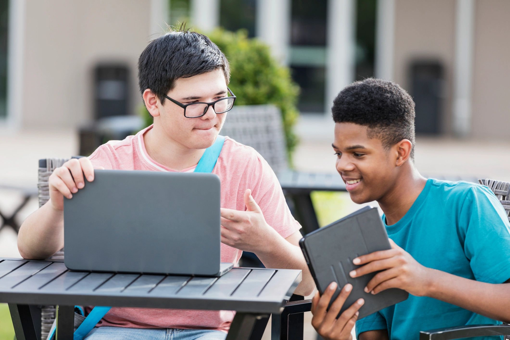 Two students working together on a laptop outdoors