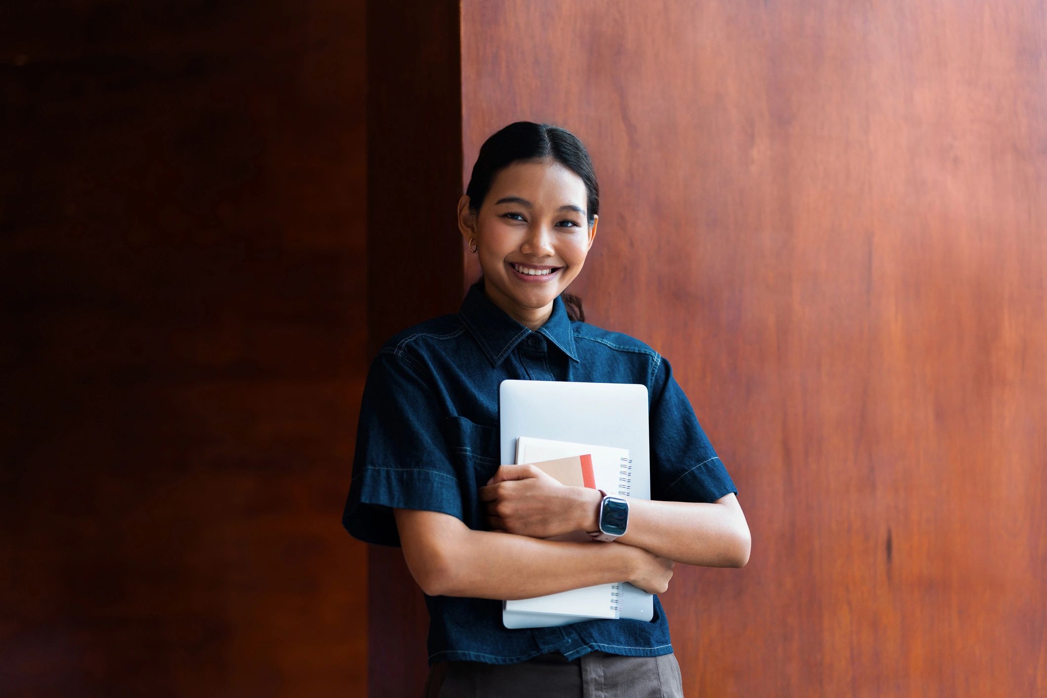 Smiling student holding a laptop and notebook